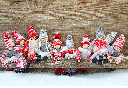 Eine Gruppe von weihnachtlichen Fingerpuppen sitzt auf einem verschneiten Ast.