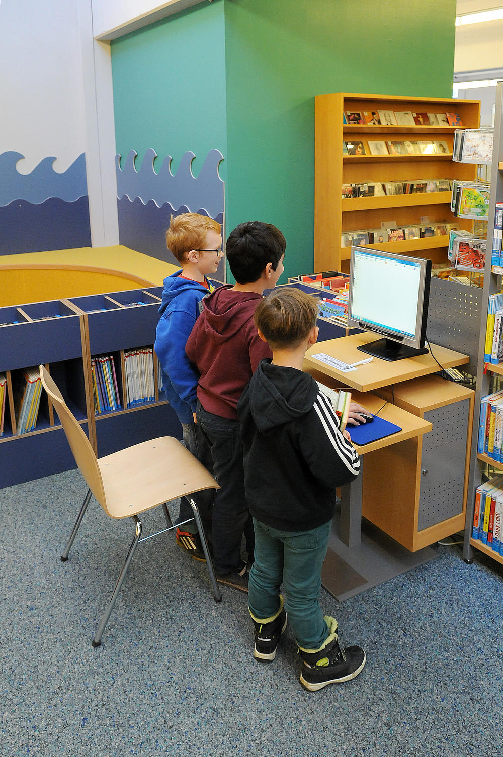 Drei Jungs stehen an einem Computerterminal in der Bücherei Husum.