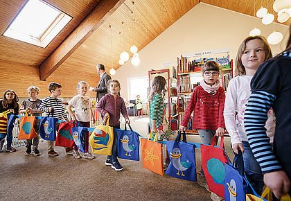 Kindern bilden eine Kette mit den Jutebeuteln des Projektes „LeseLachmöwe”.